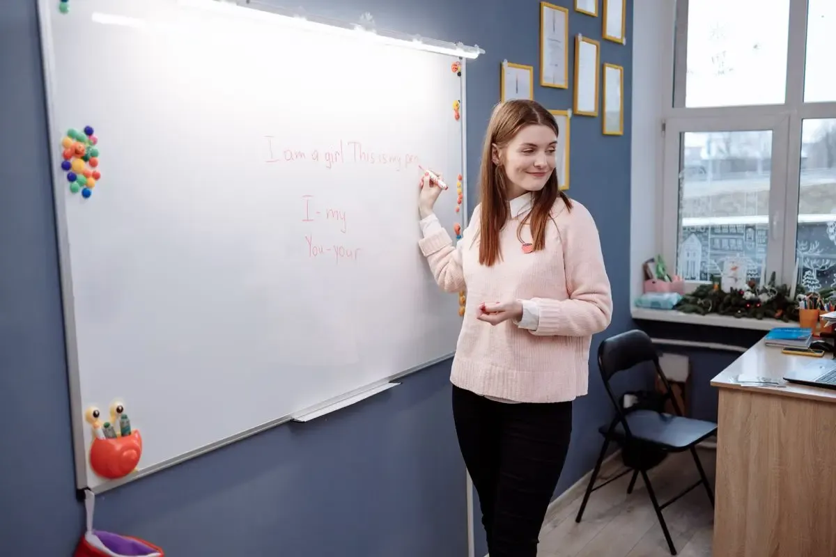 Profesora escribiendo en la pizarra blanca durante una clase de inglés